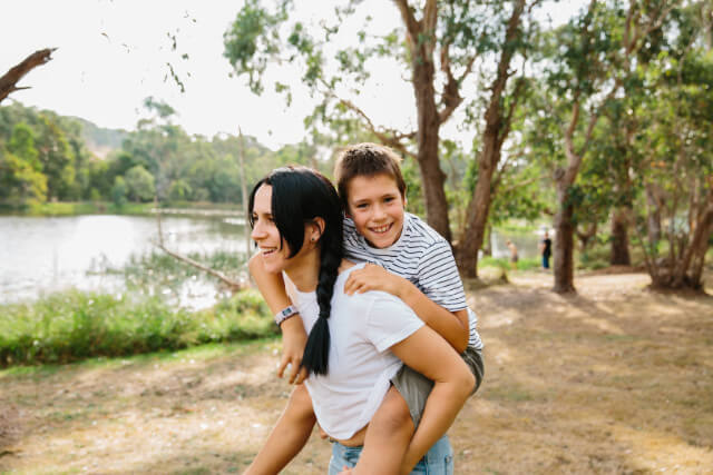 Tween boy has a piggyback ride with his mama